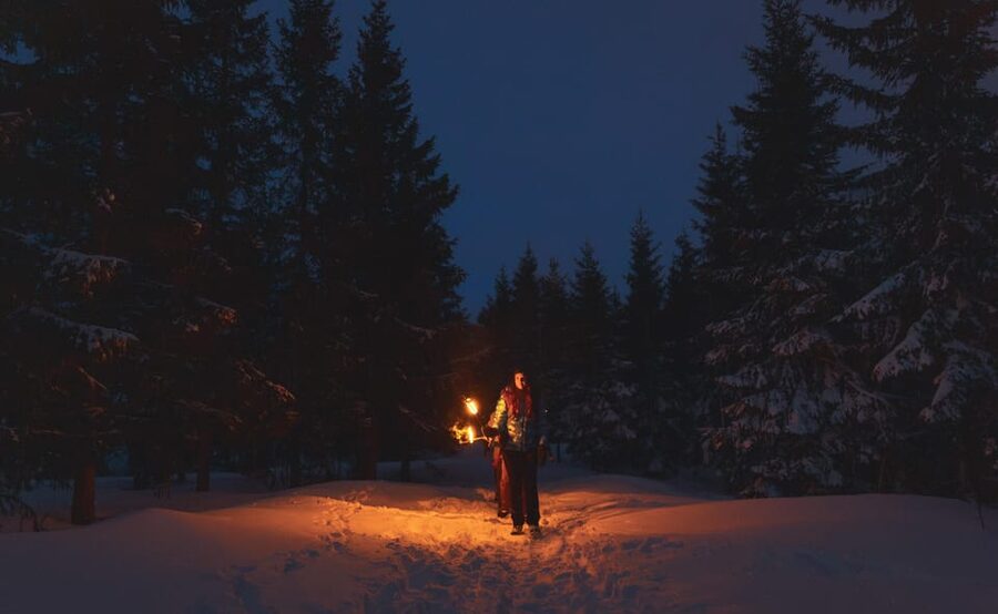 Oslo: Snowy Forest Torchlight Walk with Campfire - Holding a flame in the snowy forest